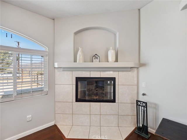 interior details featuring wood finished floors, a tile fireplace, and baseboards