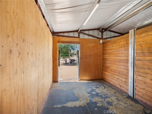 interior space featuring concrete floors, vaulted ceiling, and wood walls