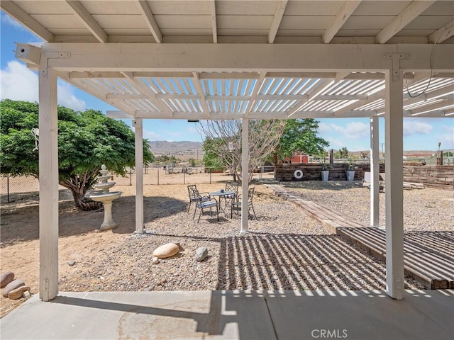 view of patio featuring outdoor dining area, fence, a mountain view, and a pergola