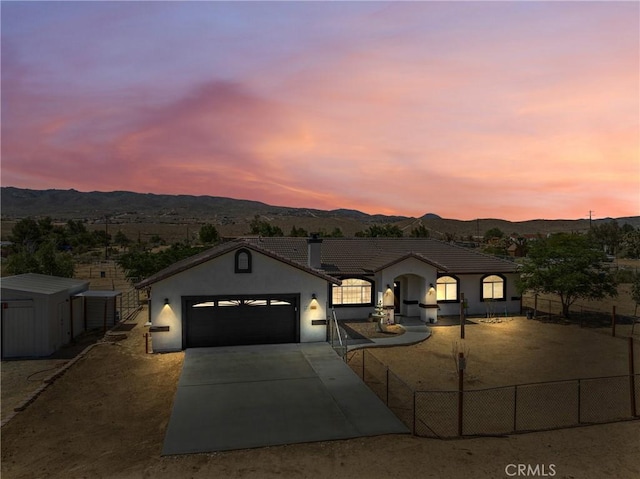 view of front of property featuring an attached garage, a mountain view, fence, driveway, and stucco siding