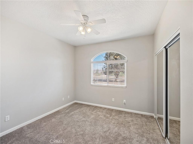 unfurnished bedroom featuring carpet, a textured ceiling, baseboards, and a closet