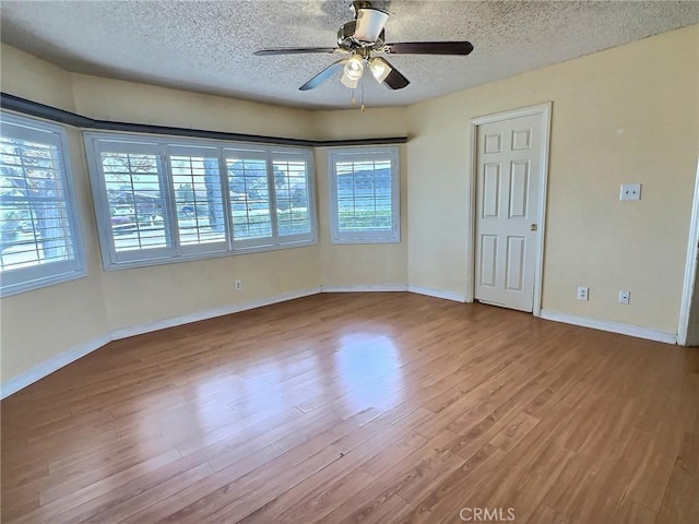 empty room featuring a ceiling fan, a textured ceiling, baseboards, and wood finished floors