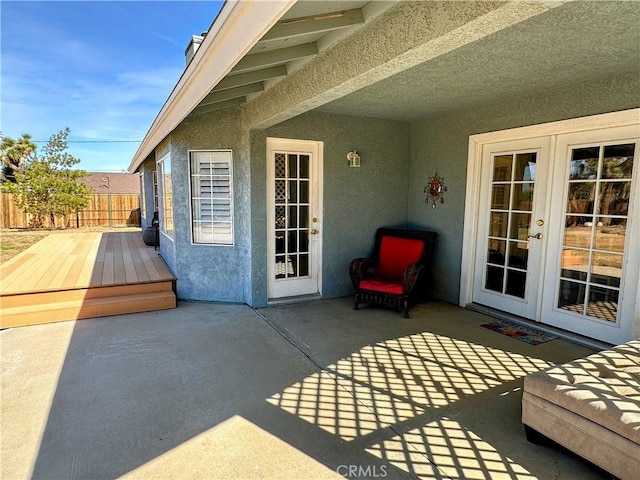 view of patio with french doors, fence, and a deck