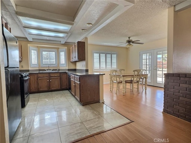 kitchen with dark countertops, a peninsula, french doors, black appliances, and a sink