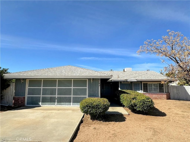 single story home with brick siding, a shingled roof, concrete driveway, an attached garage, and fence