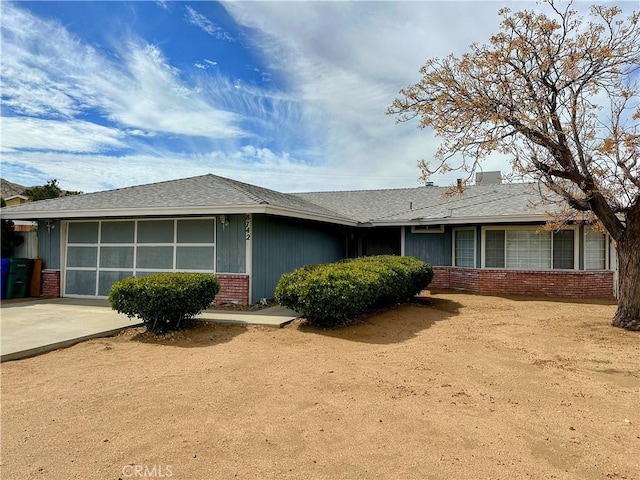 ranch-style house featuring concrete driveway, brick siding, and an attached garage