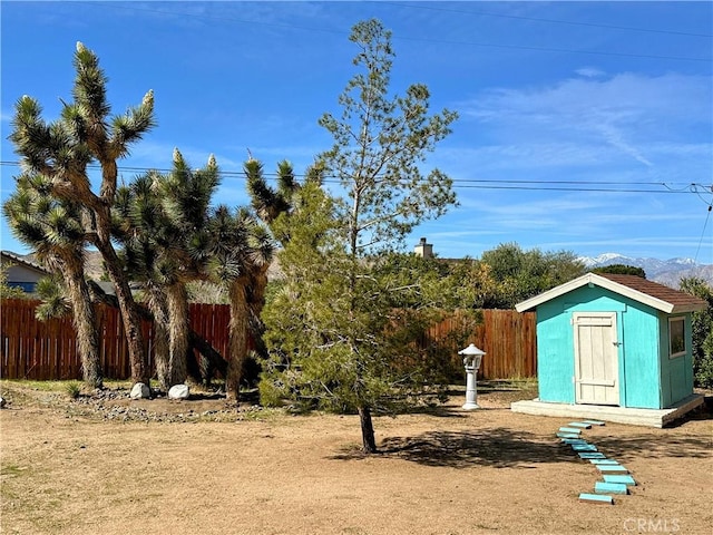 view of yard featuring a storage unit, an outdoor structure, and fence