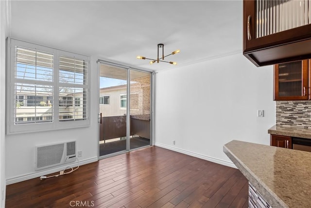 dining space with dark wood-style floors, a wall mounted air conditioner, baseboards, and an inviting chandelier