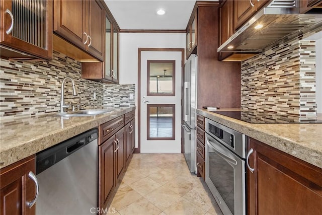 kitchen with range hood, backsplash, appliances with stainless steel finishes, glass insert cabinets, and a sink