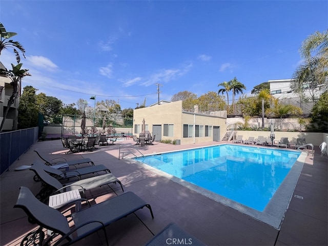 pool with stairway, fence, and a patio