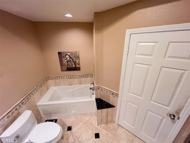 full bath with toilet, a jetted tub, tile walls, and a wainscoted wall