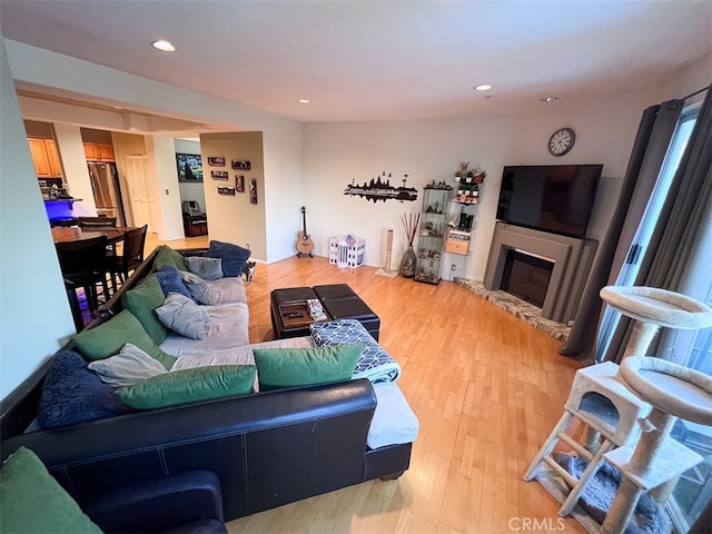 living area with a glass covered fireplace, light wood-style flooring, and recessed lighting