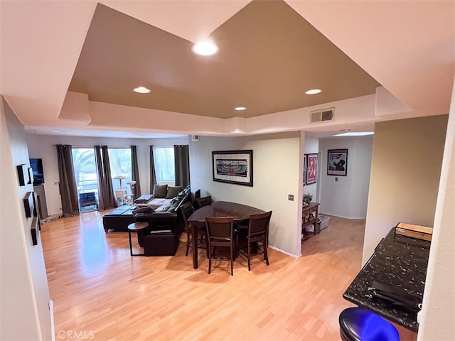 living area featuring light wood-style flooring, a raised ceiling, visible vents, and recessed lighting