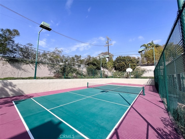 view of tennis court featuring community basketball court and fence