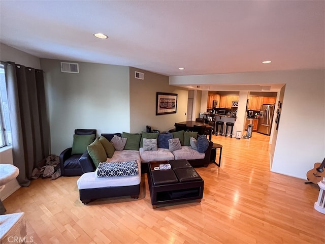 living room with light wood-type flooring, visible vents, and recessed lighting