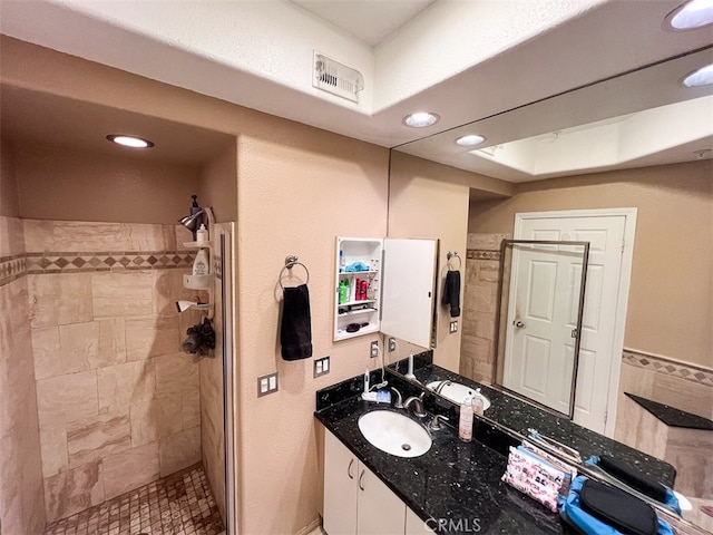 full bath featuring visible vents, a tile shower, vanity, and recessed lighting