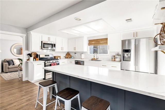 kitchen with stainless steel appliances, a breakfast bar, a sink, and tasteful backsplash