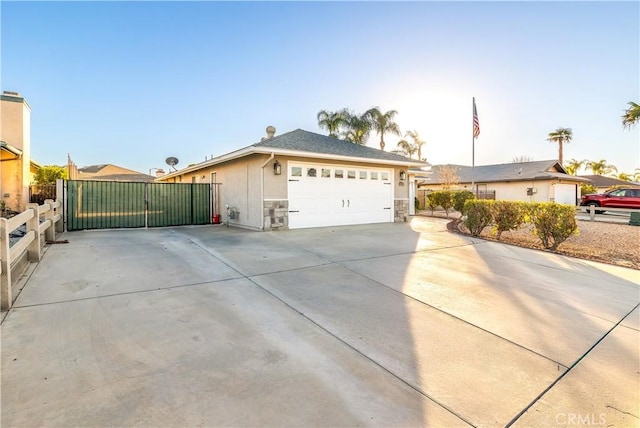 ranch-style house featuring concrete driveway, stone siding, an attached garage, a gate, and stucco siding