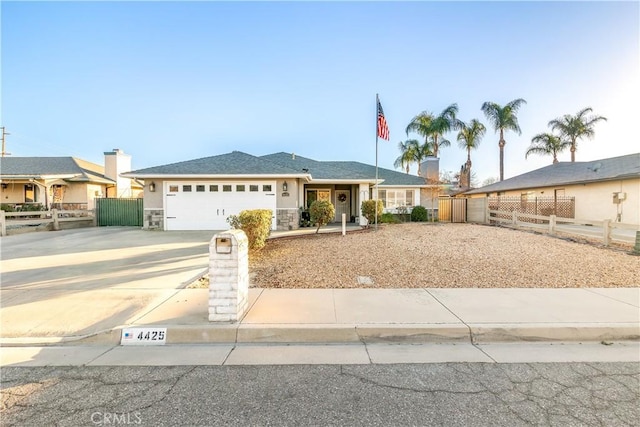 single story home featuring stucco siding, concrete driveway, an attached garage, fence, and stone siding