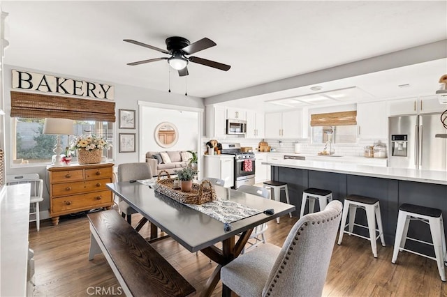 dining space with a ceiling fan and dark wood-type flooring