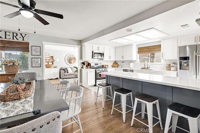 kitchen featuring stainless steel appliances, a breakfast bar, visible vents, and tasteful backsplash