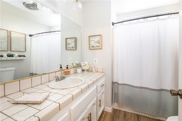 bathroom with wood finished floors, a shower with shower curtain, vanity, and toilet