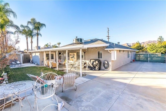 back of property featuring an outdoor hangout area, a storage unit, an outdoor structure, a patio area, and stucco siding