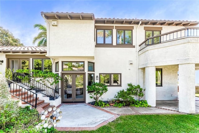 exterior space with stucco siding, a tiled roof, a patio area, and french doors