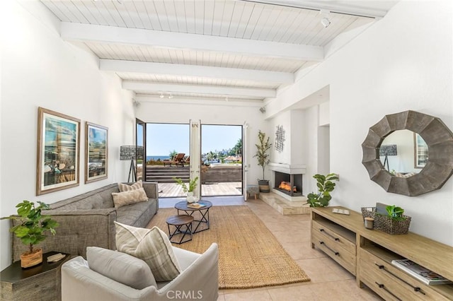 interior space with wooden ceiling, light tile patterned floors, a warm lit fireplace, and beamed ceiling