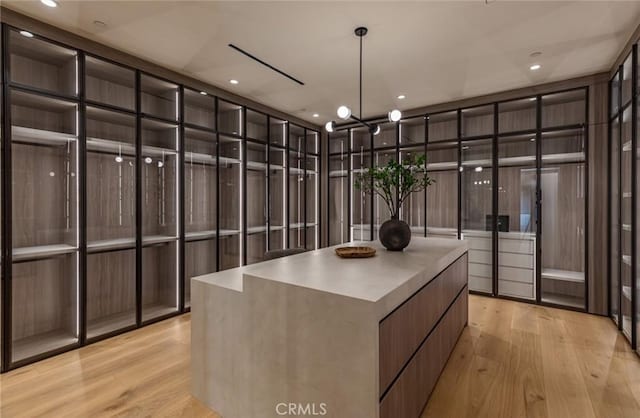 walk in closet featuring light wood-style floors and an inviting chandelier