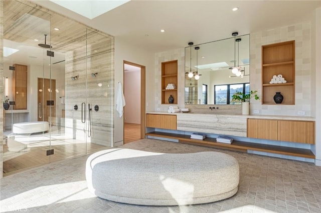 bathroom featuring a stall shower, a skylight, vanity, and built in features