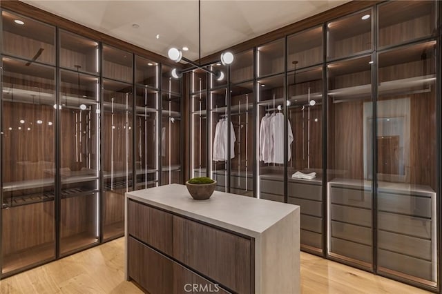 walk in closet featuring light wood-type flooring and an inviting chandelier