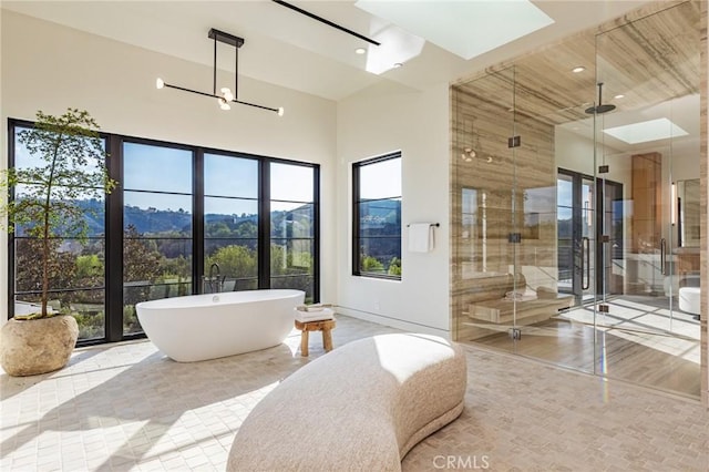 bathroom featuring a stall shower, a skylight, a towering ceiling, a soaking tub, and recessed lighting