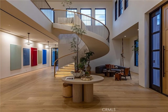 foyer with light wood-type flooring, a towering ceiling, and stairway