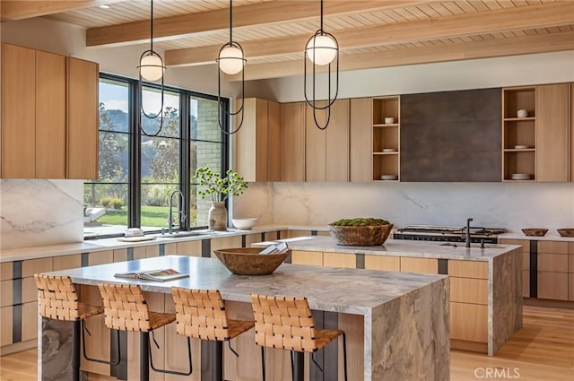 kitchen with decorative backsplash, modern cabinets, a center island, open shelves, and a sink