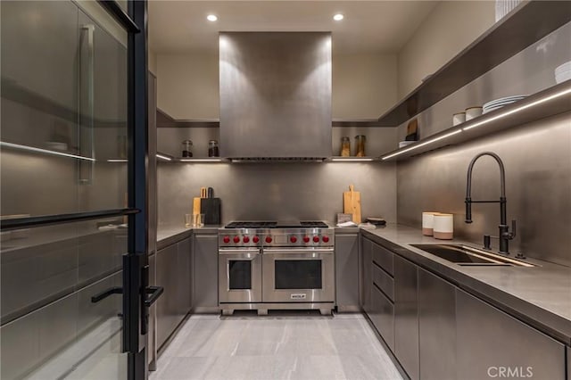 kitchen featuring open shelves, range with two ovens, ventilation hood, and a sink