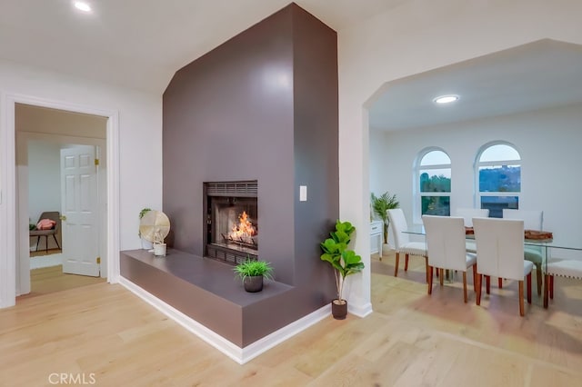 interior space with recessed lighting, a lit fireplace, baseboards, and wood finished floors