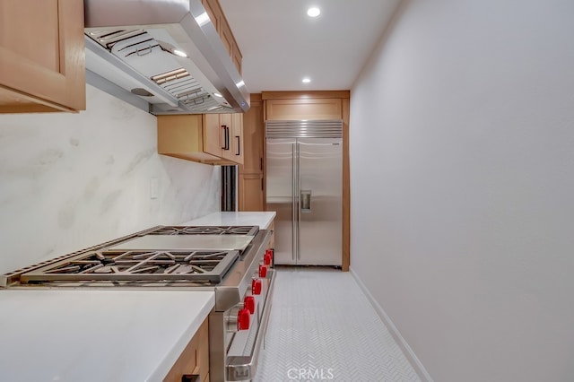 kitchen featuring high quality appliances, baseboards, light countertops, ventilation hood, and light brown cabinetry