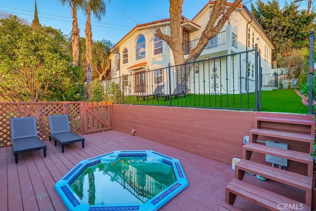 exterior space with hot tub deck surround, a lawn, and fence