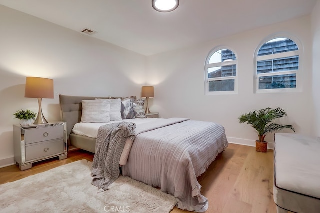 bedroom featuring light wood-type flooring, visible vents, and baseboards