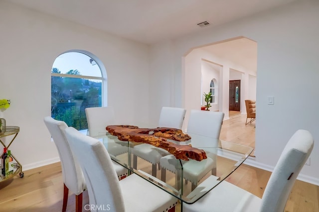 dining space featuring light wood-style flooring, visible vents, and baseboards