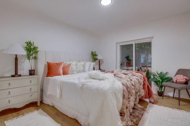 bedroom with access to outside and wood finished floors