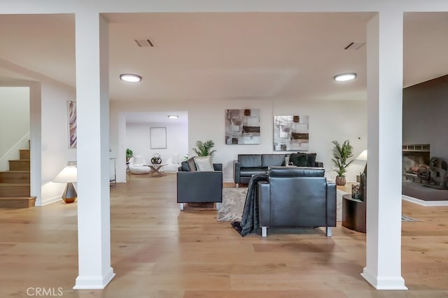 living room featuring light wood-style floors, visible vents, a fireplace, and stairs