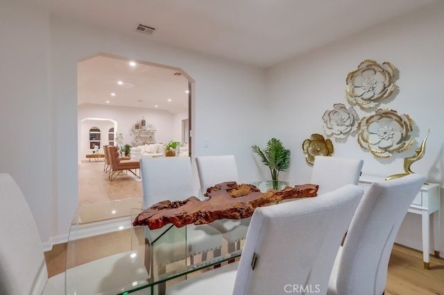 dining area with visible vents, arched walkways, wood finished floors, and recessed lighting