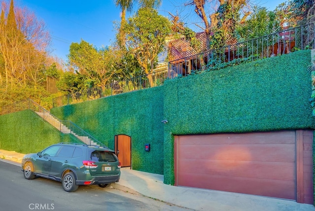 view of front facade featuring a garage, fence, and stairway