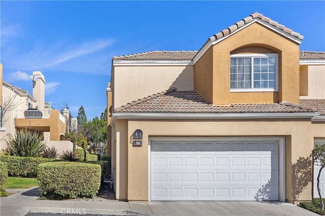 view of front of home featuring a garage, a tile roof, concrete driveway, and stucco siding