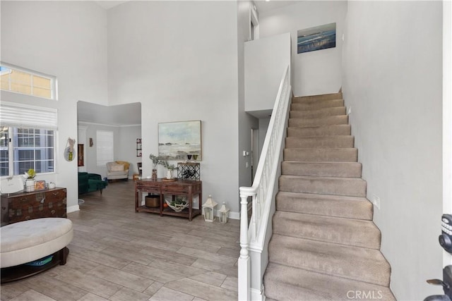 stairs with a towering ceiling, baseboards, and wood finished floors