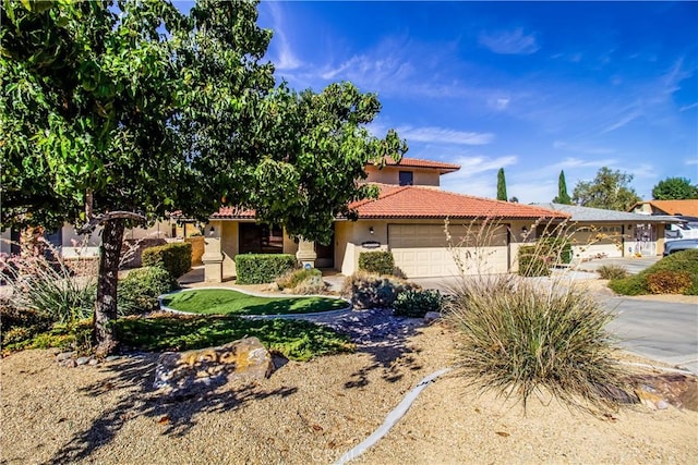 view of front facade with driveway, a tiled roof, an attached garage, and stucco siding