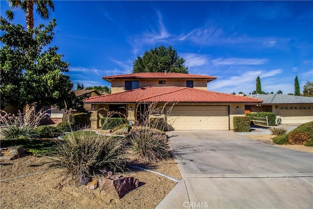 mediterranean / spanish-style house with concrete driveway, an attached garage, a tile roof, and stucco siding