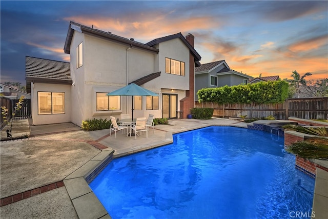 pool at dusk featuring a fenced in pool, a patio, and a fenced backyard